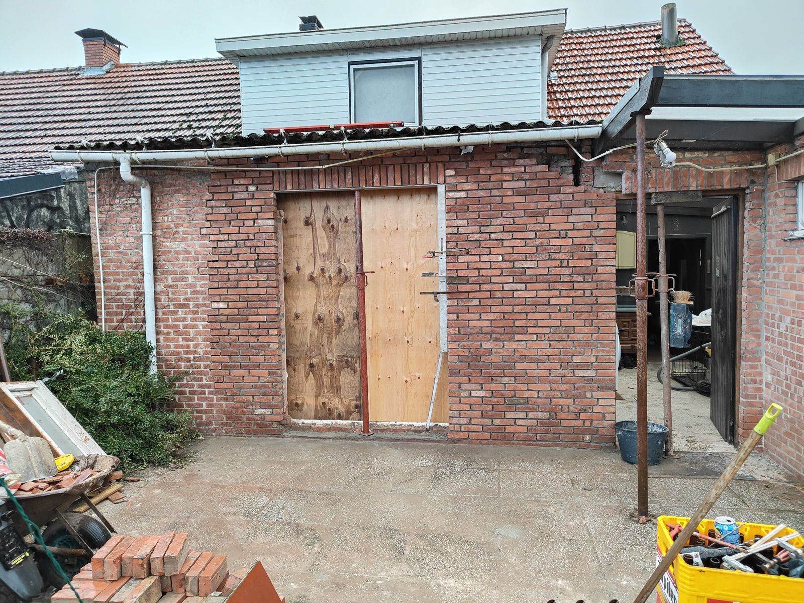Dichtgemetselde garagepoort met nieuwe deuropening in baksteen