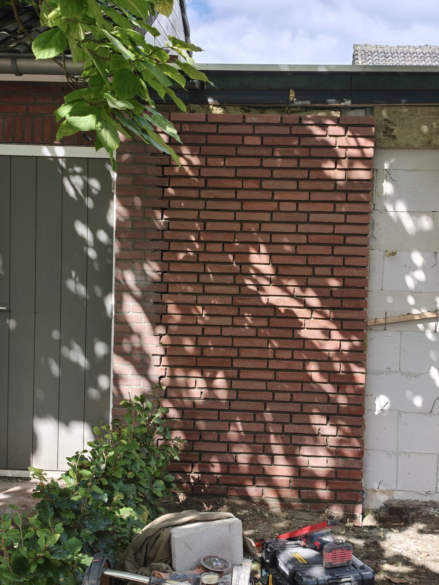 Dichtgemetselde en afgewerkte baksteengevel tussen garage en woning