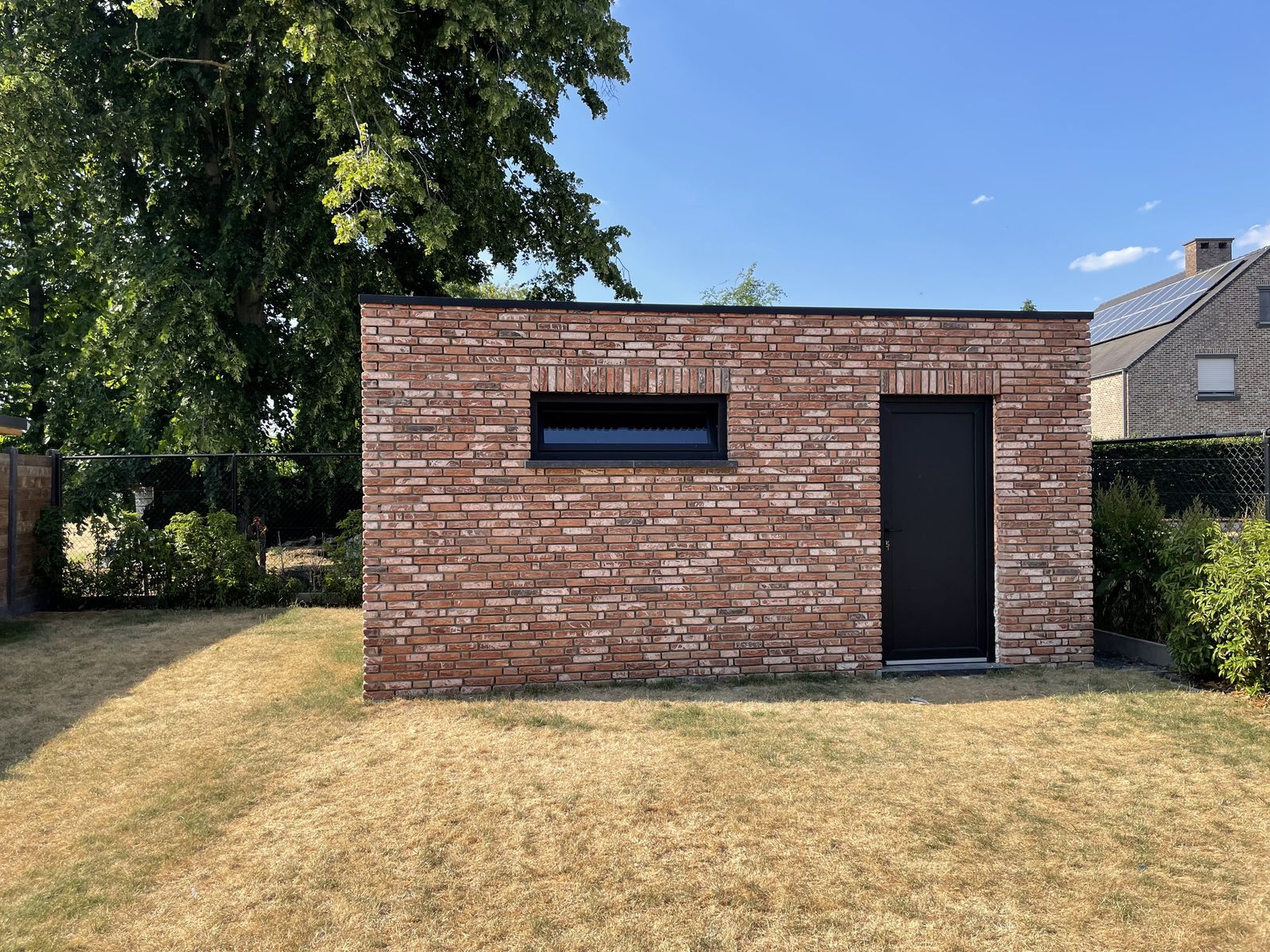 Gemetseld bijgebouw met plat dak, raam en deur