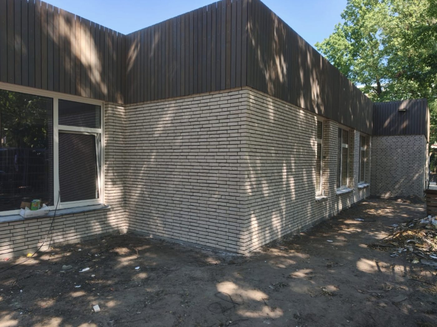 Moderne woning met gevel in witte steenstrips naast houten gevelbekleding