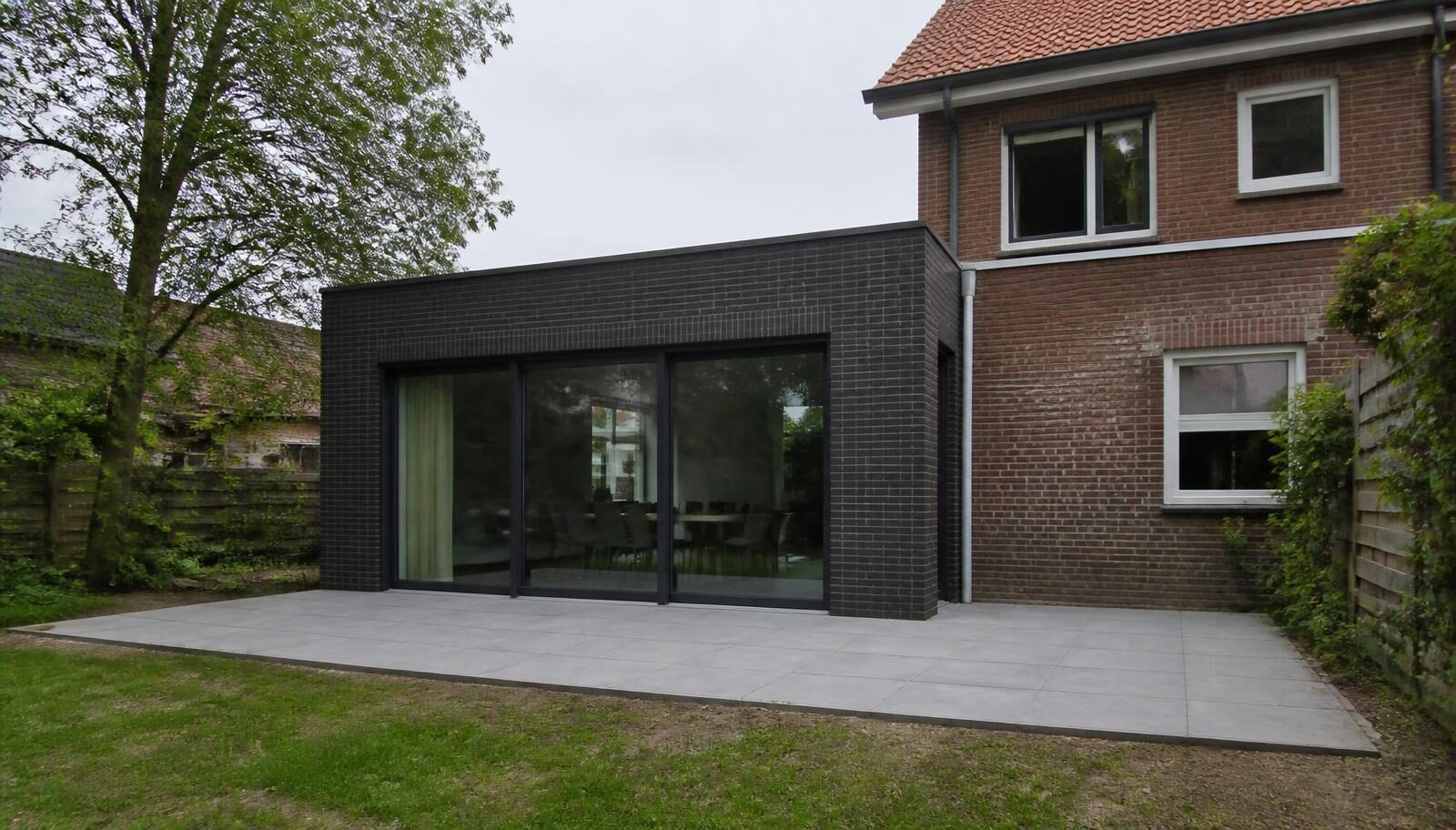 Moderne aanbouw aan een bestaande woning, gezien vanuit de tuin